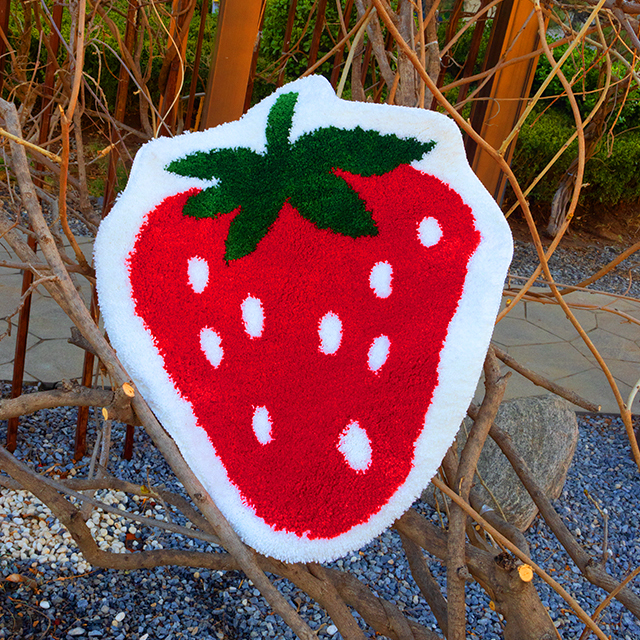 Adorable strawberry-shaped tufted carpet with vibrant red hues, green leaf details, and soft, fuzzy pile – crafted for cozy comfort underfoot. Made from child-safe materials like polyester or cotton.
